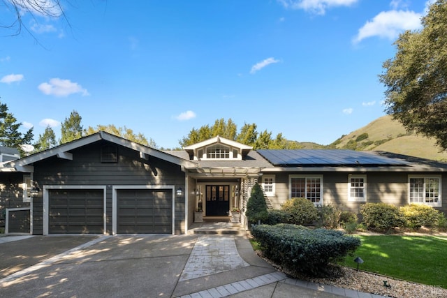 single story home featuring solar panels, concrete driveway, and an attached garage