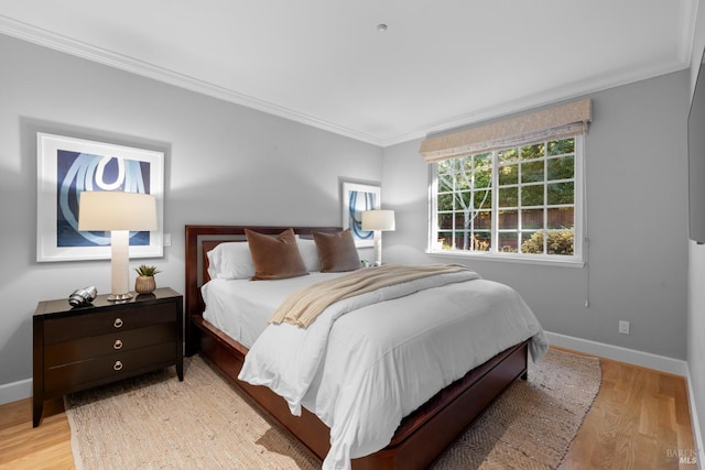 bedroom featuring ornamental molding, light wood-style flooring, and baseboards