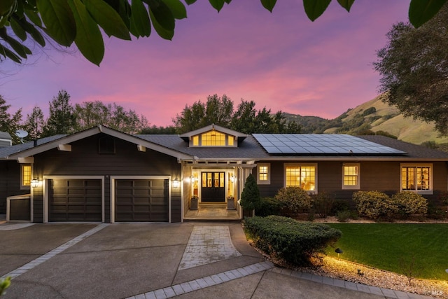 view of front of home featuring a garage, roof mounted solar panels, and concrete driveway