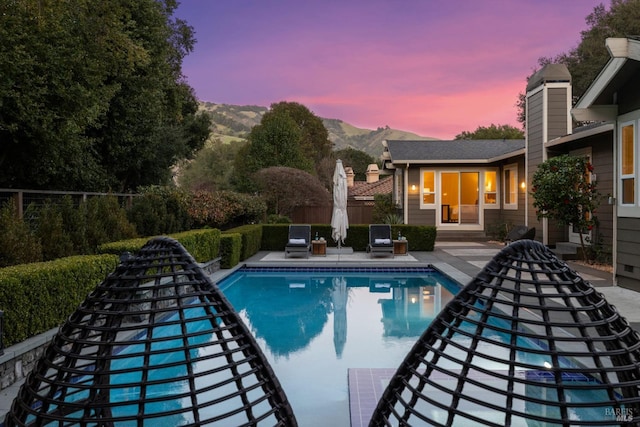 outdoor pool featuring fence, a mountain view, and a patio