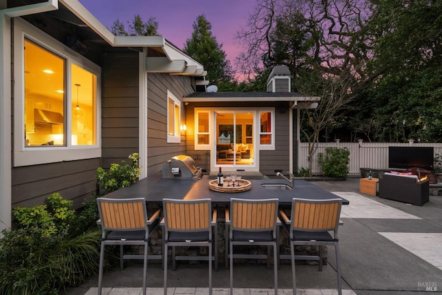 view of patio / terrace with a sink, outdoor dining area, fence, and a grill