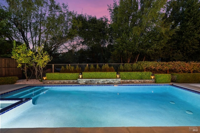 pool at dusk featuring fence and a fenced in pool