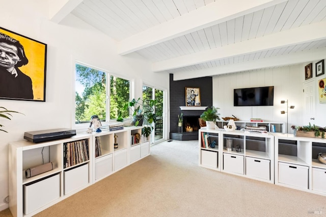 living room featuring beam ceiling, a brick fireplace, and light carpet