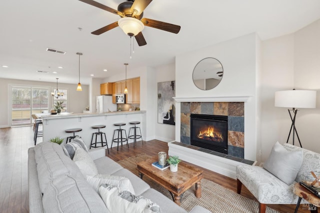 living area featuring light wood-style floors, visible vents, a tiled fireplace, and recessed lighting