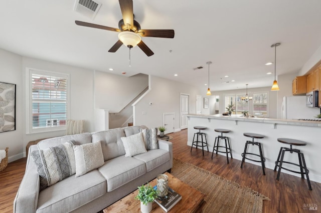 living room with dark wood-type flooring, a healthy amount of sunlight, visible vents, and stairs