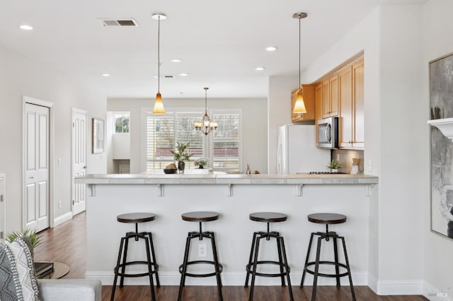 kitchen featuring light countertops, stainless steel microwave, a kitchen bar, and decorative light fixtures