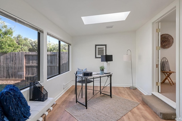 office area featuring a skylight, wood finished floors, and baseboards