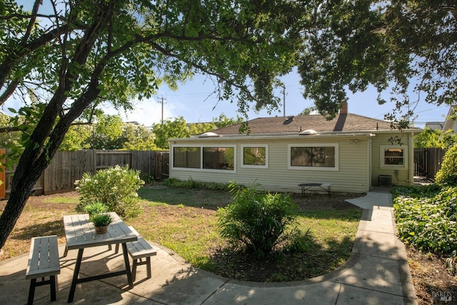 back of house with outdoor dining area, a chimney, a patio area, and fence private yard