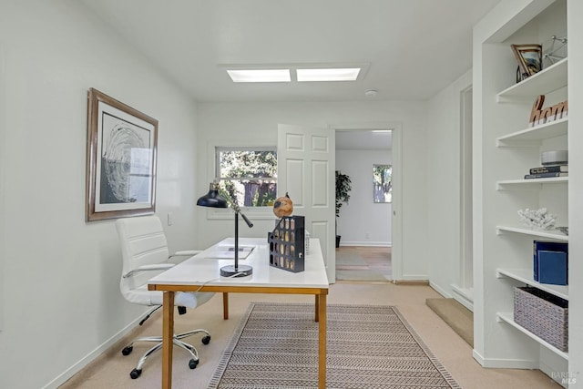 office area featuring built in features, light colored carpet, and baseboards