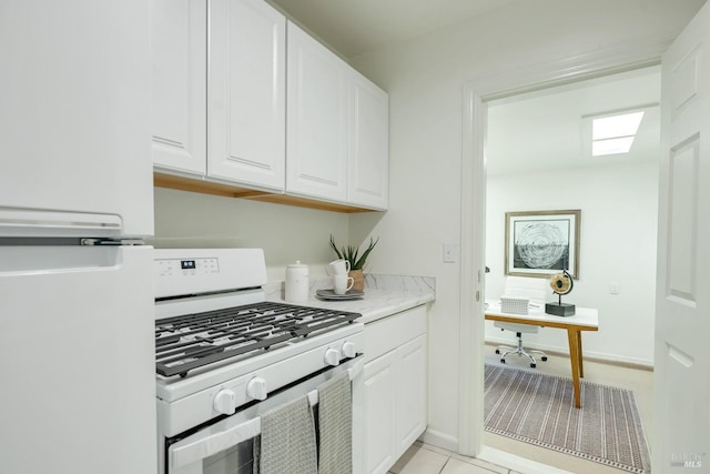 kitchen with baseboards, light countertops, white appliances, and white cabinets