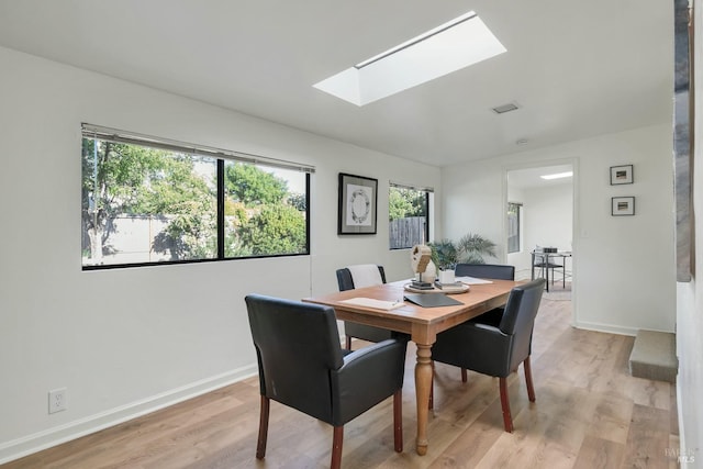 dining room with visible vents, a skylight, light wood-style flooring, and baseboards