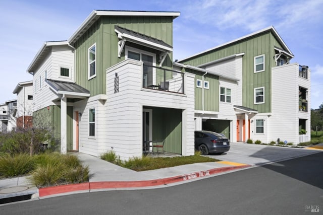 townhome / multi-family property with metal roof, an attached garage, a balcony, board and batten siding, and a standing seam roof