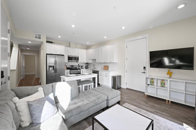 living room with dark wood-style floors, recessed lighting, visible vents, and baseboards