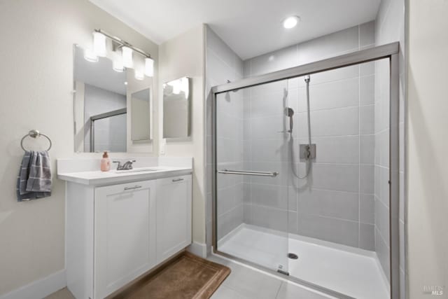 full bathroom with a stall shower, baseboards, and vanity