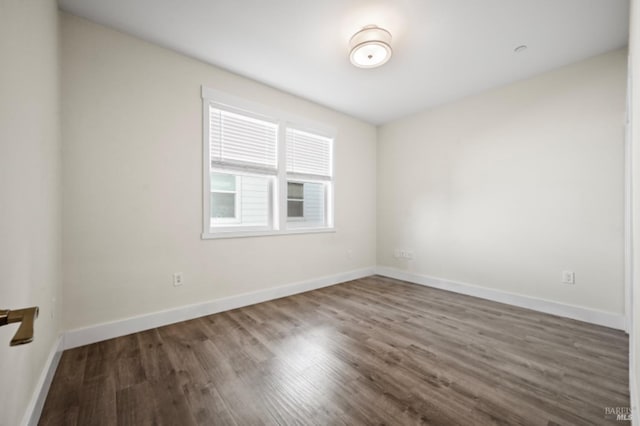 spare room with dark wood-type flooring and baseboards