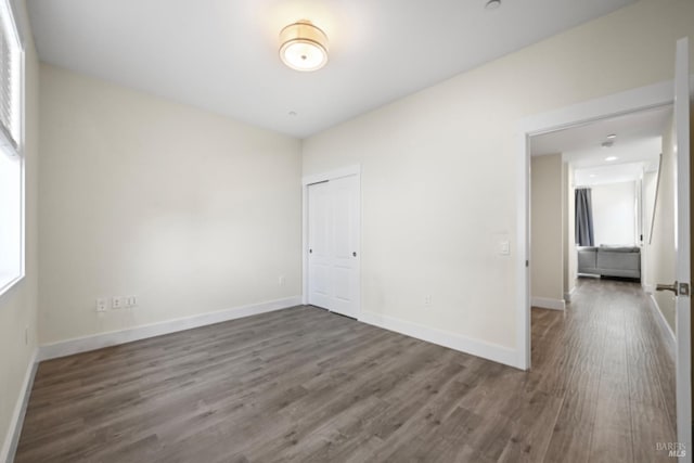 unfurnished room with dark wood-style floors and baseboards