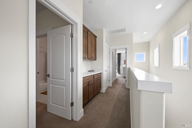 hallway with dark colored carpet, visible vents, and recessed lighting