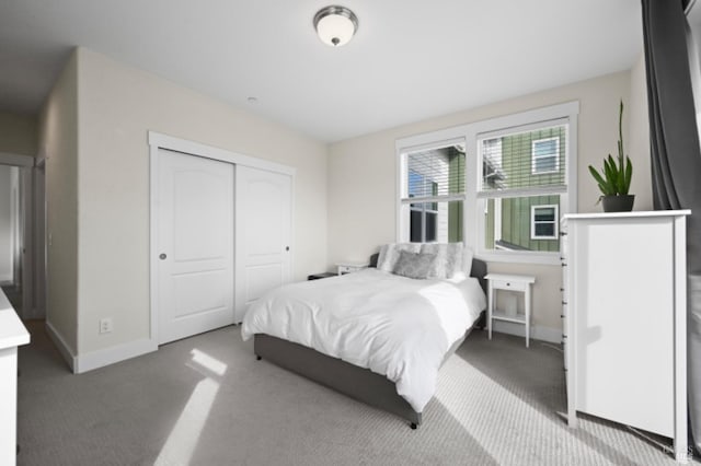 bedroom with a closet, light carpet, and baseboards