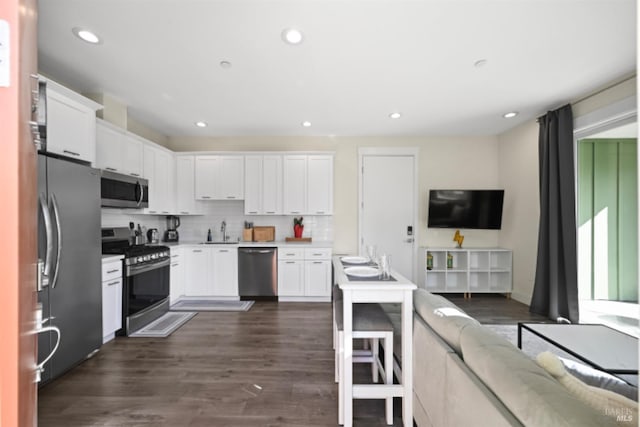 kitchen featuring decorative backsplash, open floor plan, stainless steel appliances, light countertops, and white cabinetry