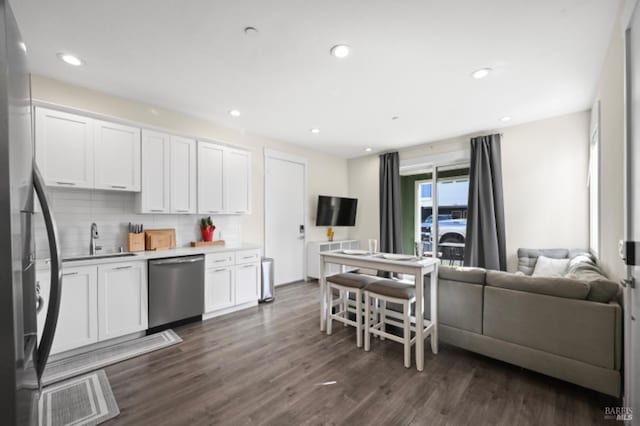 kitchen with stainless steel appliances, white cabinets, open floor plan, light countertops, and backsplash