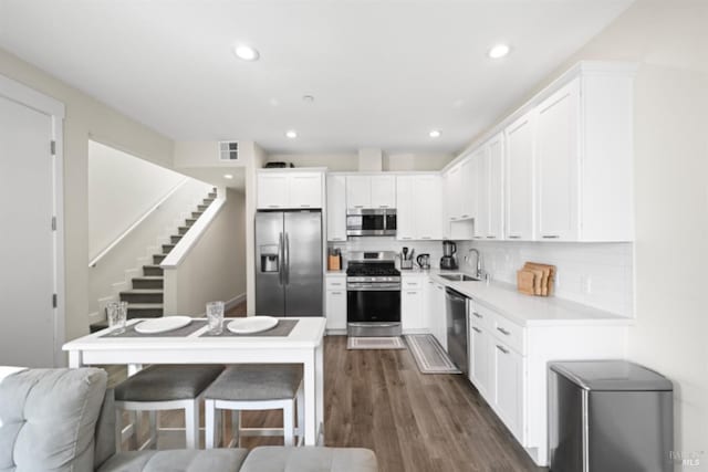 kitchen featuring stainless steel appliances, light countertops, decorative backsplash, white cabinetry, and a sink