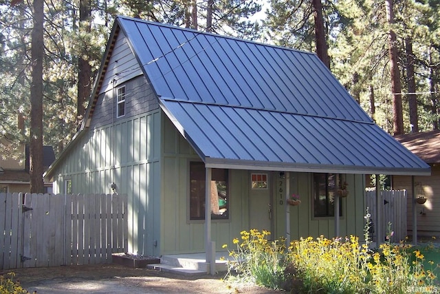 exterior space featuring a standing seam roof, fence, metal roof, and board and batten siding