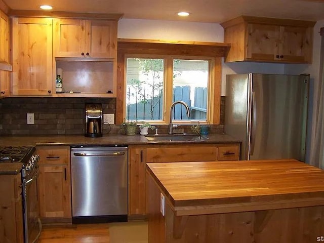 kitchen with stainless steel appliances, recessed lighting, decorative backsplash, a sink, and butcher block countertops