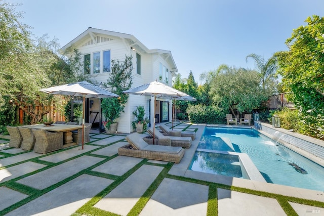 rear view of house with a patio area, a pool with connected hot tub, and fence