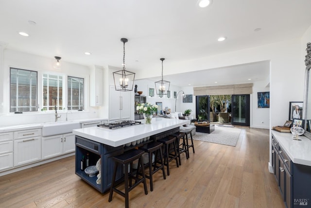 kitchen with light wood-style flooring, a breakfast bar, a sink, open floor plan, and stainless steel gas stovetop