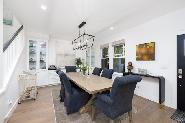 dining area with light wood-style flooring, a notable chandelier, and recessed lighting