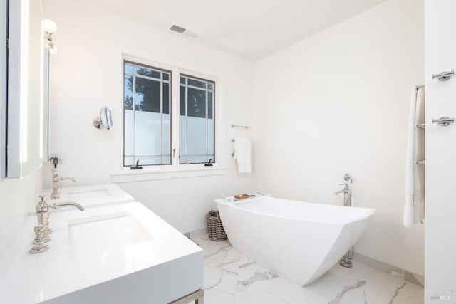 full bathroom featuring marble finish floor, visible vents, a soaking tub, and double vanity