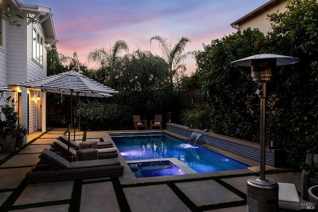 pool featuring a patio area, a fenced backyard, and an in ground hot tub