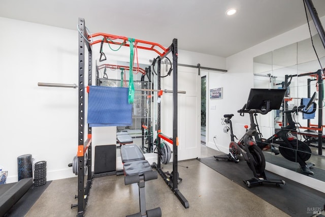 exercise area featuring baseboards, a barn door, and recessed lighting