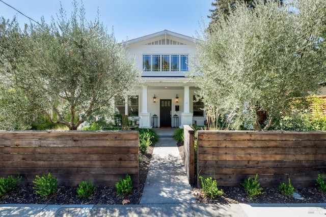 view of front of property featuring a fenced front yard, covered porch, and a gate