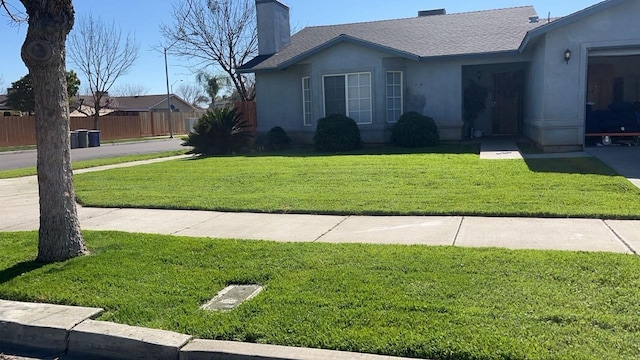 view of front facade featuring fence, roof with shingles, stucco siding, a front lawn, and a chimney