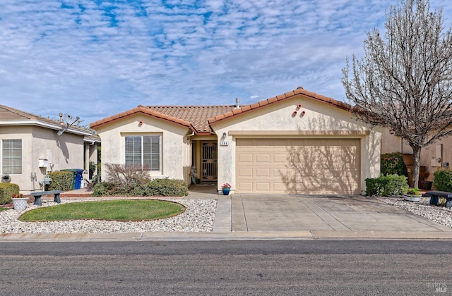 mediterranean / spanish-style home with concrete driveway, an attached garage, a tiled roof, and stucco siding