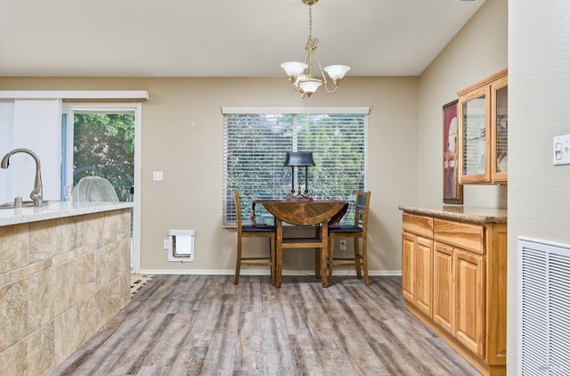 dining room featuring baseboards, a chandelier, visible vents, and light wood-style floors