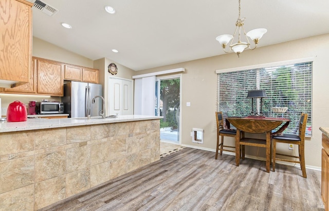 kitchen featuring decorative light fixtures, light wood finished floors, stainless steel appliances, visible vents, and a sink