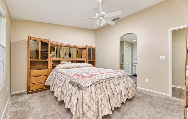 bedroom featuring light carpet, visible vents, arched walkways, and baseboards