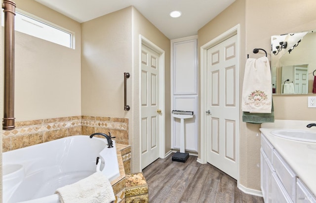 full bath with a garden tub, wood finished floors, and vanity