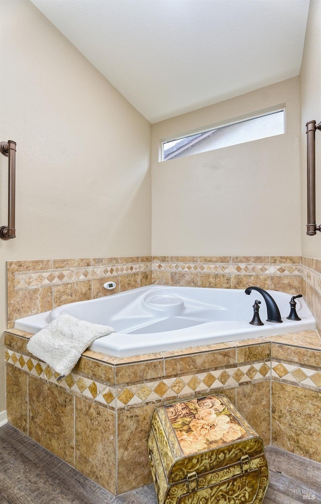 full bath featuring a relaxing tiled tub and a healthy amount of sunlight