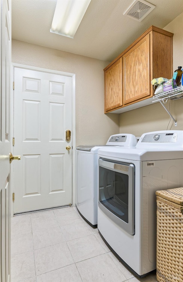 clothes washing area featuring cabinet space, washing machine and dryer, light tile patterned floors, and visible vents