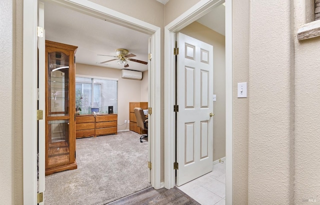 corridor with baseboards, an AC wall unit, and light colored carpet