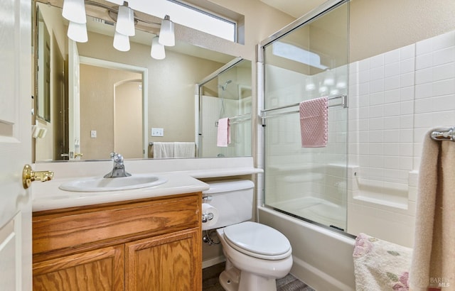 bathroom with combined bath / shower with glass door, vanity, and toilet