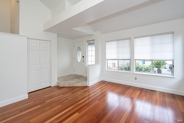 foyer entrance with baseboards, visible vents, and hardwood / wood-style floors