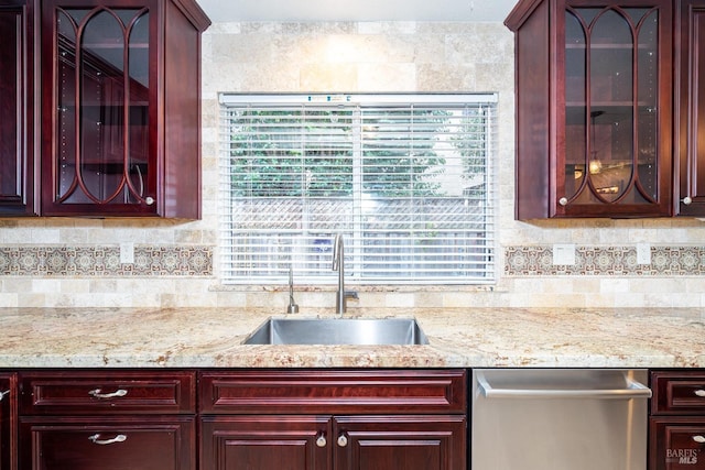 kitchen with stainless steel dishwasher, a sink, dark brown cabinets, and tasteful backsplash