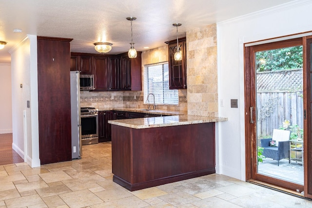 kitchen featuring stainless steel appliances, stone tile flooring, backsplash, a sink, and a peninsula