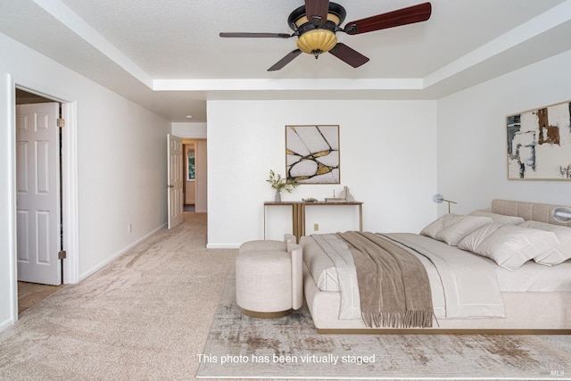 bedroom with a raised ceiling, carpet flooring, and baseboards