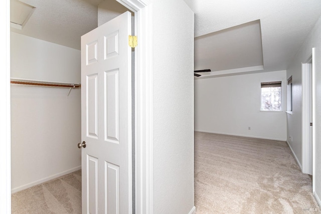 corridor with carpet flooring, a textured ceiling, and baseboards