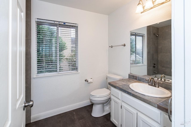 bathroom featuring toilet, baseboards, wood finished floors, and vanity